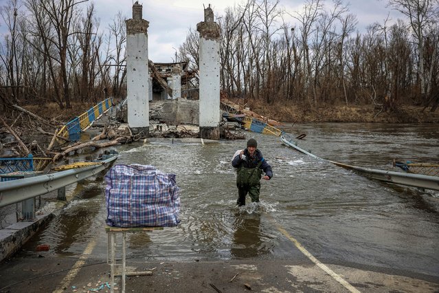 A local resident of the village of  Bohorodychne cross the Siversky Donets river at a destroyed bridge to retrieve bread from the other bank, in Bohorodychne, Donetsk Oblast, on March 10, 2023, amid Russia's military invasion on Ukraine. (Photo by Anatolii Stepanov/AFP Photo)