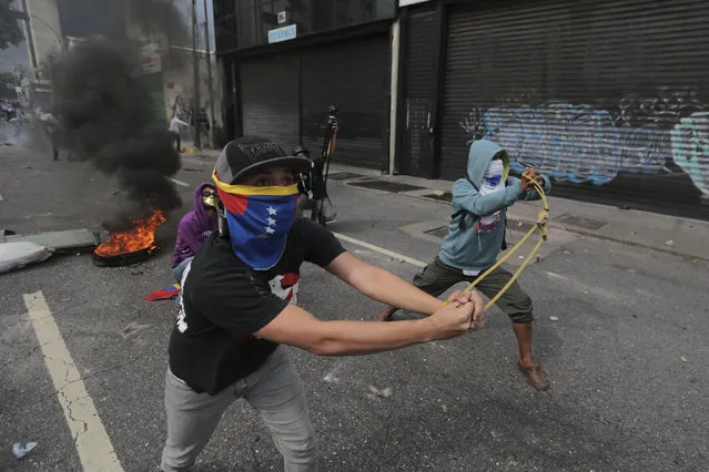 Anti-government protesters launch stones with a sling during clashes in Caracas, Venezuela, Wednesday, April 19, 2017. Tens of thousands of opponents of President Nicolas Maduro flooded the streets of Caracas in what's been dubbed the “mother of all marches” against the embattled socialist president. (Photo by Fernando Llano/AP Photo)