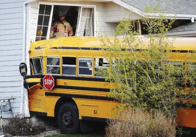 Rescue personnel work a site where a bus crashed into a house, Tuesday, May 6, 2014, in Sioux Falls, S.D. Police say the bus hit one house, then crossed the street and crashed into another house. There were no children on the bus at the time of the crash, and the bus driver, 66, was taken to the hospital with a head injury. (Photo by Joe Ahlquist/AP Photo/Argus Leader)