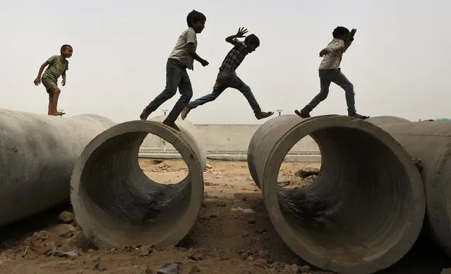 Children play on cement sewer pipes near a construction site in Ahmedabad, India, May 5, 2016. (Photo by Amit Dave/Reuters)