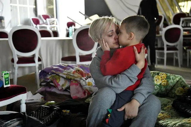 Egor, 5, comforts his mother Helen Yakubets who cries in a ballroom, which has been converted to a temporary shelter, at the Mandachi hotel after fleeing from Chernihiv in Ukraine to Romania, following Russia's invasion of Ukraine, at the border crossing in Suceava, Romania, March 20, 2022. Her 18 year old son and husband remain in Ukraine to fight. (Photo by Clodagh Kilcoyne/Reuters)