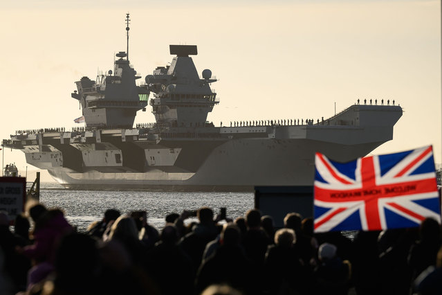 Members of the public watch as Naval personnel perform procedure alpha as they stand on deck during the arrival of the United Kingdom's biggest warship, the HMS Prince of Wales aircraft carrier, following a three months deployment, on December 11, 2023 in Portsmouth, England. HMS Prince of Wales recently finished sea and air trials in the eastern United States, enhancing the capabilities of UK's aircraft carriers, especially in launching and landing F-35s under challenging weather conditions. (Photo by Leon Neal/Getty Images)