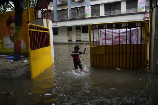 A boy plays in the flooded water at an entrance door after heavy rains in Mumbai, India, Monday, July 8, 2024. (Photo by Rafiq Maqbool/AP Photo)