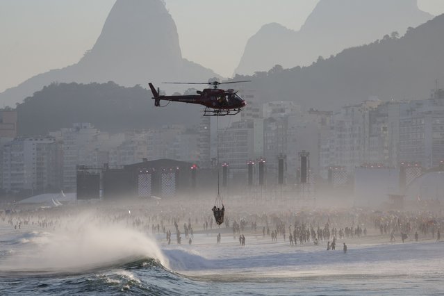 A helicopter transports lifeguards and a rescued person as people gather at Copacabana beach near the stage where Madonna will hold a concert, in Rio de Janeiro, Brazil on May 4, 2024. (Photo by Ricardo Moraes/Reuters)