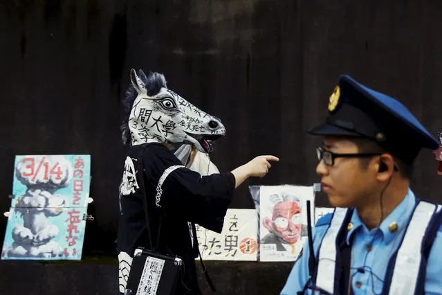A protester wears a horse mask as a police officer looks on during the third day of demonstrations against Japan's Prime Minister Shinzo Abe's security-related legislation outside the parliament building in Tokyo, July 17, 2015. Abe, pushed through parliament's lower house legislation that could see troops sent to fight abroad for the first time since World War Two, despite protests and a risk of further damage to his sagging ratings. (Photo by Thomas Peter/Reuters)