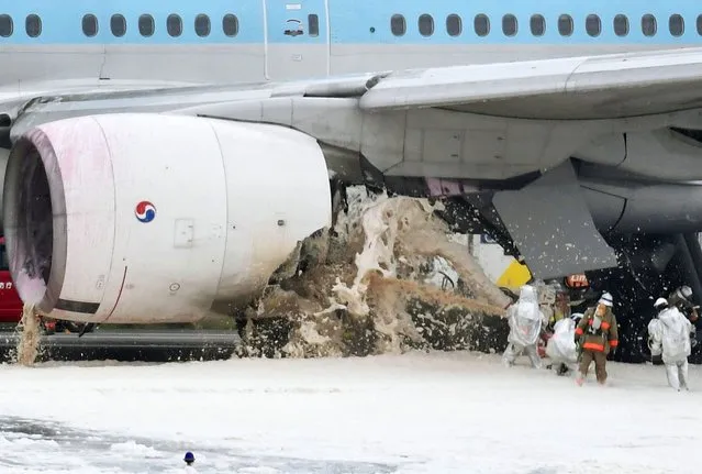 Firefighters put out fire of a Korean Air jet at the tarmac following an engine fire at Haneda Airport in Tokyo, Friday, May 27, 2016. The engine fire broke out on the jet about to take off from the airport on Friday, and some people may have been injured, an airport official said. (Photo by Naohiko Hatta/Kyodo News via AP Photo)