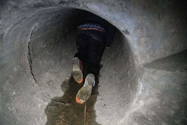 A protester crawls within a sewer tunnel to see how wide it is as he and others try to find an escape route from the Hong Kong Polytechnic University in the Hung Hom district of Hong Kong, early morning on November 19, 2019. Arms covered in cling film and torches in hand as they drop into the sewers, clusters of pro-democracy protesters still inside the Hong Kong campus are plotting increasingly ingenious – and desperate – ways to escape a police siege. (Photo by Anthony Wallace/AFP Photo)