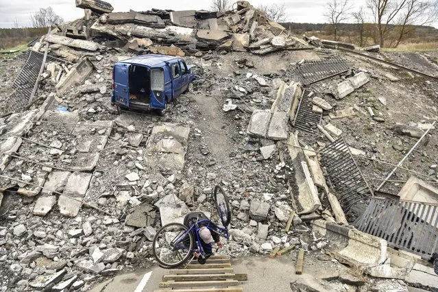 A man carries a bicycle over a destroyed bridge in Kyiv (Kiev) area, Ukraine, 19 April 2022. On 24 February Russian troops had entered Ukrainian territory resulting in fighting and destruction in the country, a huge flow of refugees, and multiple sanctions against Russia. (Photo by Oleg Petrasyuk/EPA/EFE)