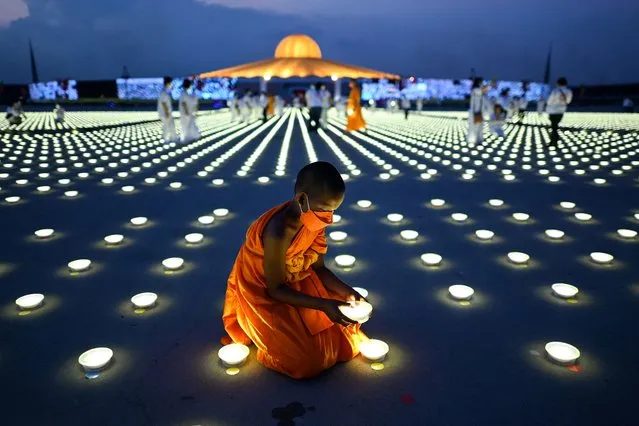 A young Buddhist monk arranges a LED light as part of Earth Day celebrations at the Wat Dhammakaya Buddhist temple in Pathum Thani province, north of Bangkok on April 22, 2022. (Photo by Manan Vatsyayana/AFP Photo)