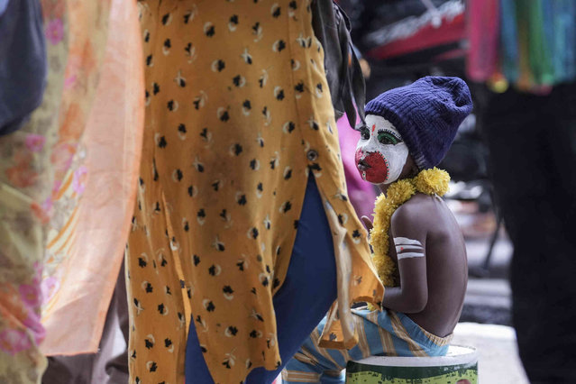 A boy sits dressed as Hindu monkey god Hanuman seeking alms outside a temple in Hyderabad, India, Friday, August 9, 2024. (Photo by Mahesh Kumar A./AP Photo)