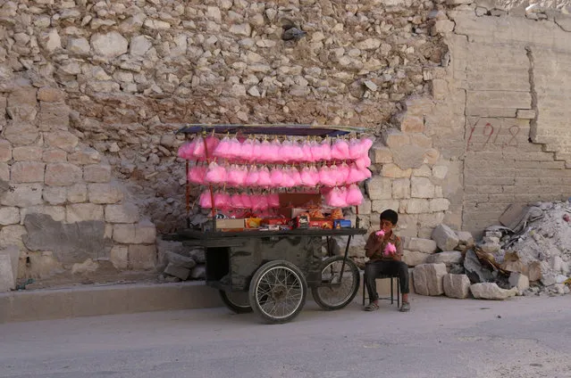 A Syrian child eats candy floss while selling it on a street cart in the Syrian city of al- Bab in the northern Aleppo province on May 15, 2017. (Photo by Zein Al Rifai/AFP Photo)
