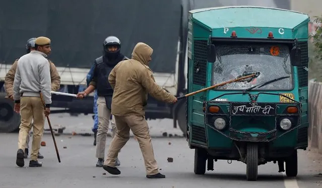 A police officer breaks a car windshield during a protest against a new citizenship law in Seelampur, area of Delhi, India December 17, 2019. (Photo by Danish Siddiqui/Reuters)