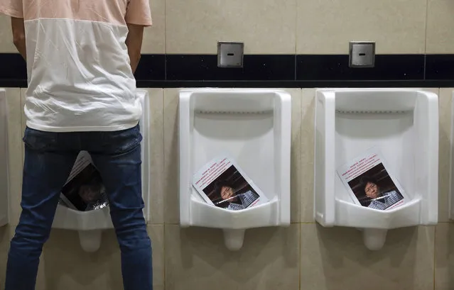 A man urinates on photos of Hong Kong Chief Executive Carrie Lam placed in the urinals, during a demonstration at the Airport in Hong Kong, Tuesday, August 13, 2019. Protesters severely crippled operations at Hong Kong's international airport for a second day Tuesday, forcing authorities to cancel all remaining flights out of the city after demonstrators took over the terminals as part of their push for democratic reforms. (Photo by Vincent Yu/AP Photo)