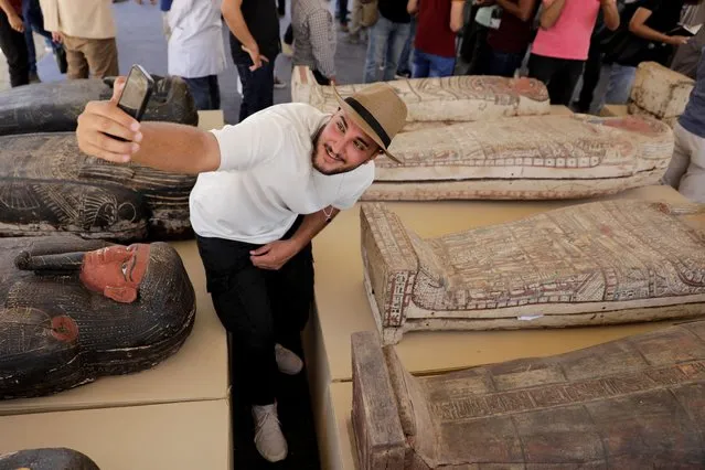 A man takes a selfie next to displayed sarcophaguses that are around 2500 years old, from the newly discovered burial site near Egypt's Saqqara necropolis, during a presentation in Giza, Egypt on May 30, 2022. (Photo by Mohamed Abd El Ghany/Reuters)