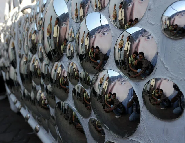 Visitors are reflected on an art installation at the annual Kala Ghoda Arts Festival in Mumbai