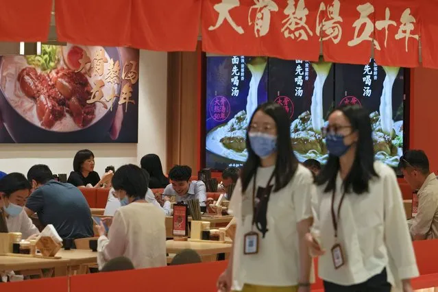 Women wearing face masks walk by a reopened restaurant in a shopping mall as new COVID-19 cases drop in Beijing Monday, June 6, 2022. (Photo by Andy Wong/AP Photo)