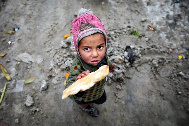 An Afghan child standing on the snow poses for a photograph at an Internal Displaced Persons (IDP) camp in downtown Kabul, Afghanistan, 13 January 2020. According to the ministry of health, at least 18 people died due to the freezing weather last week in Afghanistan. (Photo by Hedayatullah Amid/EPA/EFE)