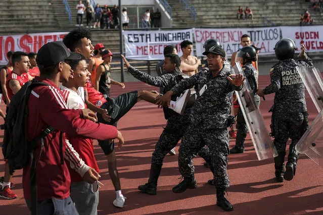 In this July 28, 2019 photo, fans of the Caracas FC soccer team clash with National Police officers before a game at Estadio Olimpico in Caracas, Venezuela. Clashes broke out when fans refused to put away banners that were considered offensive. (Photo by Matias Delacroix/AP Photo)