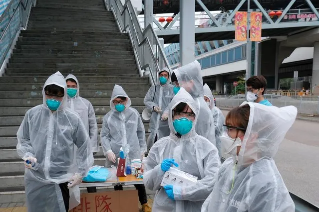 Residents wearing masks and raincoats volunteer to take temperature of passengers following the outbreak of a new coronavirus at a bus stop at Tin Shui Wai, a border town in Hong Kong, China on February 4, 2020. (Photo by Tyrone Siu/Reuters)