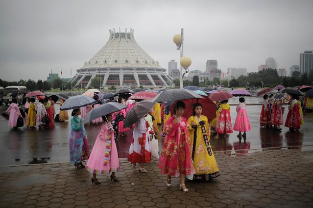 University students wearing traditional Korean dresses wait in the rain for the start of a mass dance on Thursday, July 27, 2017, in Pyongyang, North Korea as part of celebrations for the 64th anniversary of the armistice that ended the Korean War. (Photo by Wong Maye-E/AP Photo)