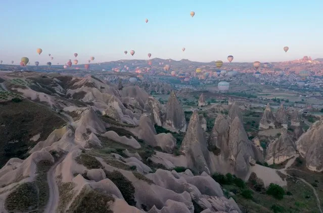 Hot-air balloons glide over the historical Cappadocia region, located in Nevsehir province of Turkiye on June 15, 2022. Cappadocia is one of the vital tourism regions of Turkiye. Tourists join the hot air balloon tour and watch the natural beauties from the sky. It is considered the center of hot air ballooning globally, as it can fly 250 days a year. Cappadocia on the UNESCO World Heritage List receives tourists from various countries for 12 months. (Photo by Behcet Alkan/Anadolu Agency via Getty Images)