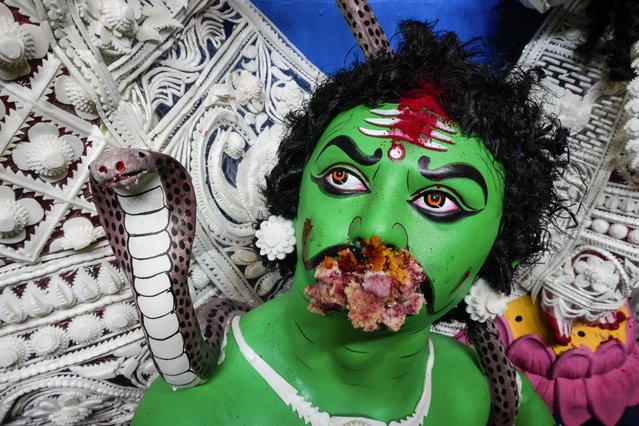 An idol of demon king, Mahisarura, a part of worship with Hindu goddess Durga, is seen with sweets fed by devotees before it is carried for immersion in the Hooghly River, in Kolkata, India, Sunday, October 13, 2024. (Photo by Bikas Das/AP Photo)