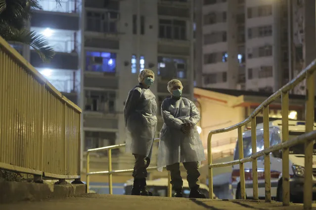 People wearing protective suits stand near the Cheung Hong Estate, a public housing estate, during evacuation of residents in Hong Kong, Tuesday, February 11, 2020. The Centre for Health Protection of the Department of Health evacuated some residents from the public housing estate after a few cases of novel coronavirus infection to stop the potential risk of further spread of the virus. (Photo by Kin Cheung/AP Photo)
