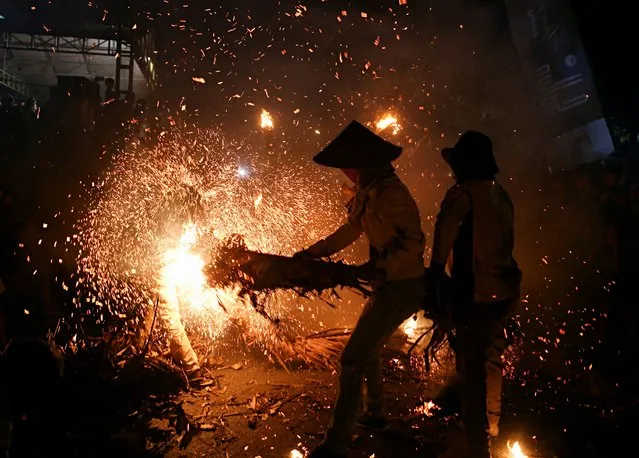 Youths play with sparks and flames from coconuts and banana leaves during a torch battle following an annual traditional event to express gratitude for the harvest and reject reinforcements in Tahunan Village, Jepara, Central Java province, Indonesia, June 20, 2022. (Photo by Dwi Oblo/Reuters)