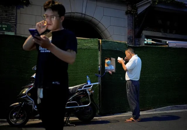  A woman chats with a man through a gap in a barrier of a sealed area, amid new lockdown measures in parts of the city to curb the coronavirus disease (COVID-19) outbreak in Shanghai, China on July 11, 2022. (Photo by Aly Song/Reuters)