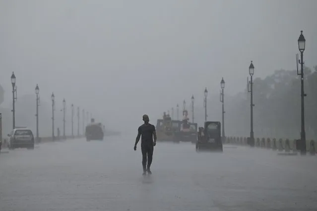 A man walks along Rajpath during a monsoon rainfall in New Delhi on July 20, 2022. (Photo by Money Sharma/AFP Photo)