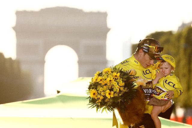 Jumbo-Visma team's Danish rider Jonas Vingegaard holds his daughter Frida as he celebrates on the podium with the overall leader's yellow jersey after winning the 109th edition of the Tour de France cycling race, after the 21st and final 115,6 km stage between La Defense Arena in Nanterre, outside Paris, and the Champs-Elysees in Paris, France, on July 24, 2022. (Photo by Christian Hartmann/Reuters)