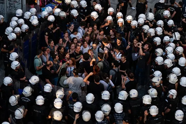Police officers surround protesters during a rally, in Kadikoy district, in Istanbul, on July 20, 2022. Called to mark on the anniversary of the 2015 suicide attack that took place in the southern Turkish town of Suruc. Leftist youth gathered to protest as they mark the anniversary of a suicide bomb attack which killed 34 people in Suruc, where activists had gathered to prepare for an aid mission to the nearby Syrian town of Kobani. It was one of the deadliest attacks in Turkey in recent years, and, the first time the government has directly accused the Islamic State group of carrying out an act of terror on Turkish soil. (Photo by Yasin Akgul/AFP Photo)