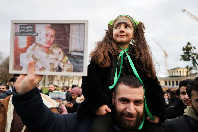 7-year-old Retal Raadon sits on the shoulders of her father Ali Raadon, who are Syrian refugees from Hama who fled to Germany in 2015, as Ali holds up a picture of a family member who they say was killed by the regime, during a celebration, after Syrian rebels announced that they have ousted Syria's Bashar al-Assad, in Bonn, Germany, on December 8, 2024. (Photo by Wolfgang Rattay/Reuters)