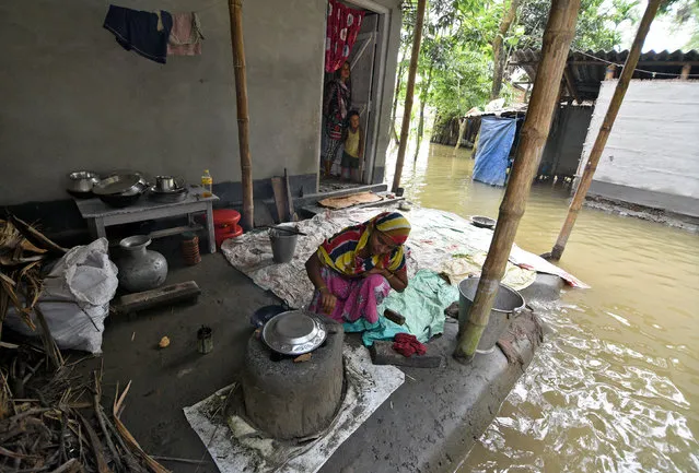 A woman prepares food outside her partially submerged house in a flood-affected village in Sonitpur district in Assam, September 11, 2017. (Photo by Anuwar Hazarika/Reuters)
