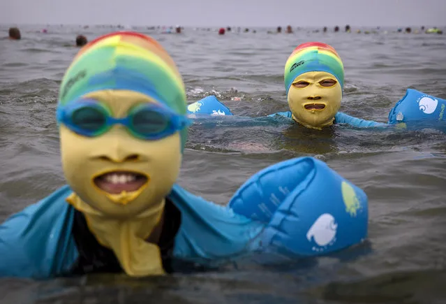 A Chinese woman and her daughter wear face-kinis while swimming on August 22, 2014 in the Yellow Sea in Qingdao, China. The locally designed mask is worn by many local women to protect them from jellyfish stings, algae and the sun's ultraviolet rays. (Photo by Kevin Frayer/Getty Images)