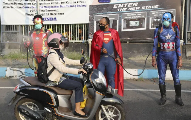 Police officers in superhero costumes spray disinfectant on motorists passing by during a coronavirus awareness campaign on a street in Pasuruan, East Java, Indonesia, Thursday, April 9, 2020. (Photo by Trisnadi/AP Photo)