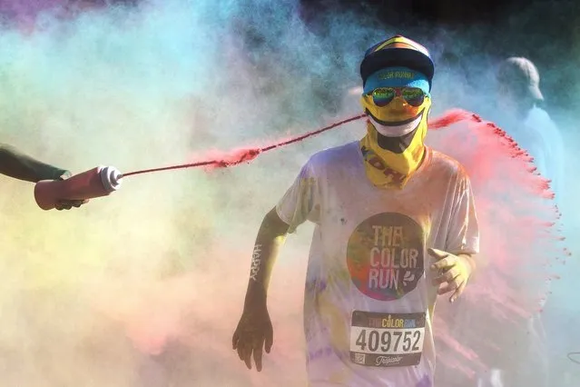 A participant crosses the finish line of the Color Run's Tropicolor World Tour in downtown Grand Rapids, Mich., Saturday, August 5, 2016. (Photo by Allison Farrand/The Grand Rapids Press via AP Photo)