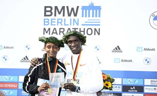 Winner of the men's race Kenya's Eliud Kipchoge (R) and winner of the women's race Ethiopia's Tigist Assefa pose on the podium after the Berlin Marathon on September 25, 2022 in Berlin. Kipchoge has beaten his own world record by 30 seconds, running 2:01:09 at the Berlin Marathon. (Photo by Tobias Schwarz/AFP Photo)