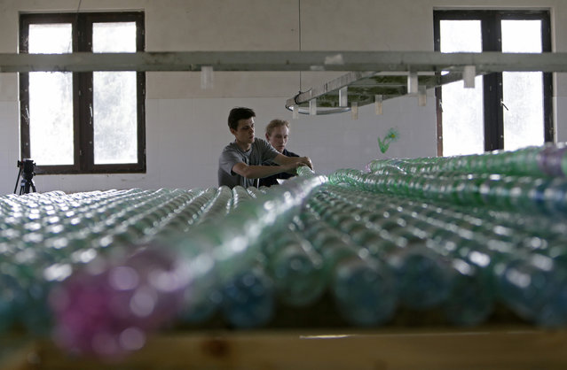 Jakub Bures (R) and Jan Kara tie plastic bottles as they build a boat in their garage in Nymburk April 3, 2014. (Photo by David W. Cerny/Reuters)