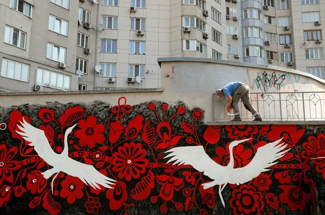Street artists paint a mural onto a wall near a building in a residential area in Kyiv, Ukraine, 18 August 2022. Ukrainian street artist Yulia Abramova, with friends and colleagues paint a mural depicting a symbolic red the tree of life and white storks as talismans, who symbolically guard Ukraine during the Russian invasion. Russian troops on 24 February entered Ukrainian territory, starting a conflict that has provoked destruction and a humanitarian crisis. (Photo by Sergey Dolzhenko/EPA/EFE/Rex Features/Shutterstock)