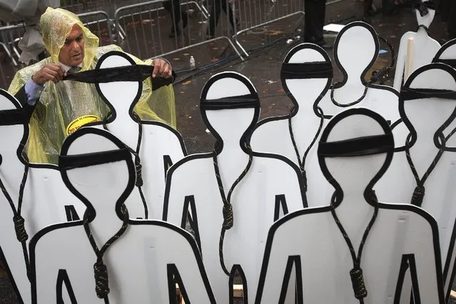 A protester ties a blindfold on effigies that have nooses around their necks near the United Nations Building as as Iranian President Hassan Rouhani speaks during the United Nations General Assembly in the Manhattan borough of New York September 25, 2014. (Photo by Carlo Allegri/Reuters)