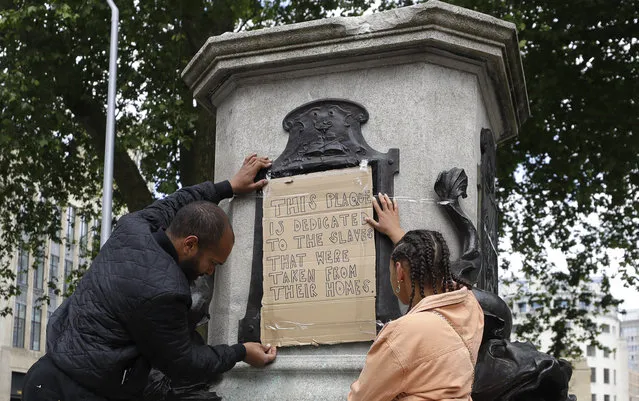 A banner is taped over the inscription on the pedestal of the toppled statue of Edward Colston in Bristol, England, Monday, June 8, 2020. The toppling of the statue was greeted with joyous scenes, recognition of the fact that he was a notorious slave trader – a badge of shame in what is one of Britain’s most liberal cities. (Photo by Kirsty Wigglesworth/AP Photo)