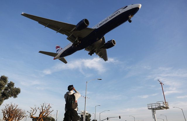 A person takes photos of a British Airways plane landing from a park next to Los Angeles International Airport (LAX) following the Christmas holiday on December 26, 2024 in Los Angeles, California. According to the Transportation Security Administration (TSA), about 40 million people will be flying during the holidays between December 19 and January 2, a six percent increase from last year. (Photo by Mario Tama/Getty Images)