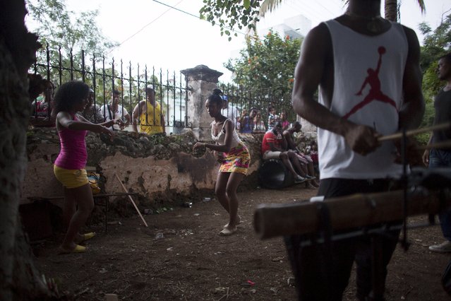 Dancers Leannis Ortega, 20, (C), and Nairobis Placers, 20, (L), take part in the party of Yensy Villarreal, 9, (not pictured), in celebration for becoming a Santero after passing a year-long rite of passage in the Afro-Cuban religion Santeria, Havana, July 5, 2015. (Photo by Alexandre Meneghini/Reuters)