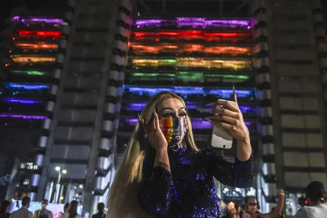 A transgender woman takes a selfie in front of the Empresas Publicas de Medellin (EPM) building illuminated with rainbow colors for Pride Month, amid de COVID 19 pandemic, in Medellin, on June 24, 2020. (Photo by Joaquin Sarmiento/AFP Photo)