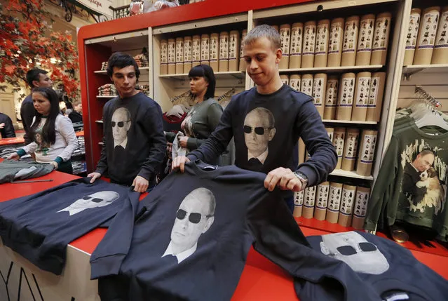 Salesman show sweatshirts with printed portraits of Russian President Vladimir Putin in the GUM department store in Moscow, Russia, 06 October 2014. The Anyavanya brand of Russian designers Anna Yefremova and Ivan Yershov presented the new collection of sweatshirt decorated by Putin prints. (Photo by Yuri Kochetkov/EPA)