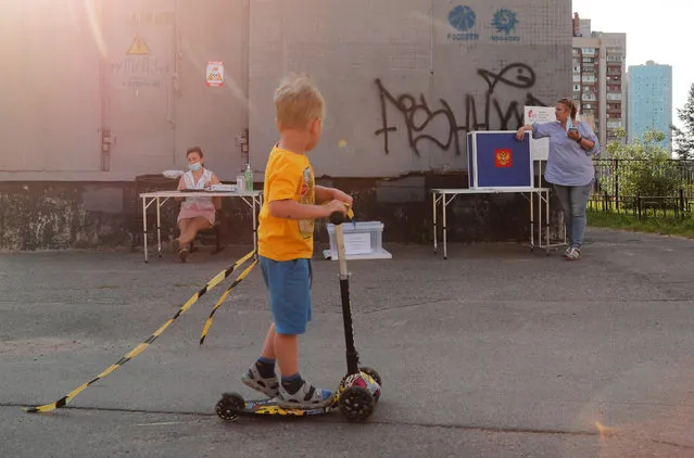 A boy rides a scooter past an outdoor polling place during a seven-day vote on constitutional reforms in Saint Petersburg, Russia on June 25, 2020. (Photo by Anton Vaganov/Reuters)