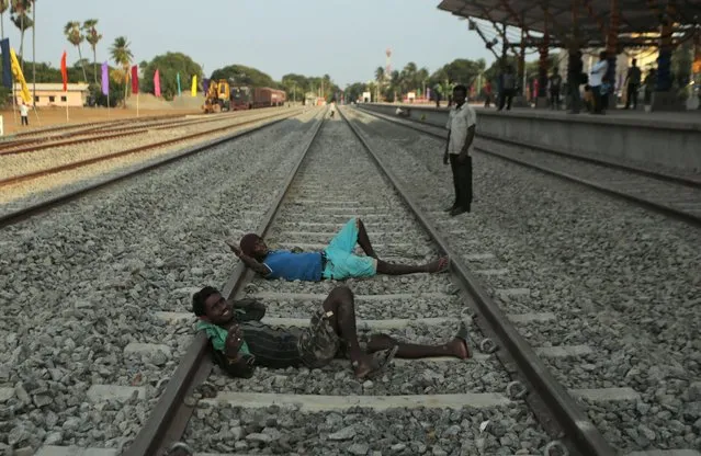 Sri Lankan ethnic Tamil workers react to the camera as they rest on a rail track at the Jaffna railway station Sri Lanka, Sunday, October 12, 2014. The “Queen of Jaffna”, a once-popular train linking the ethnic Tamil's northern heartland to the rest of Sri Lanka before a bloody civil war cut the link 24 years ago, chugs back into service this coming week, reinforcing the government's authority in a region once controlled by Tamil rebels. (Photo by Eranga Jayawardena/AP Photo)