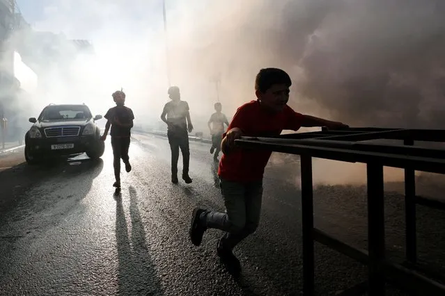 Palestinian boys play as disinfectants are sprayed by workers to sanitize cars and shops amid the coronavirus disease (COVID-19) outbreak in Hebron in the Israeli-occupied West Bank on June 28, 2020. (Photo by Mussa Qawasma/Reuters)