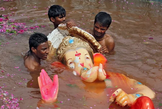 Volunteers prepare to lift an idol of the Hindu god Ganesh, the deity of prosperity, from a temporary pond after its immersion during the ten-day-long Ganesh Chaturthi festival in Ahmedabad, India, September 22, 2015. (Photo by Amit Dave/Reuters)